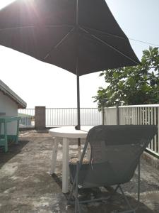 a table with an umbrella and a chair under it at La Plus Grande Source D'eaux Chaudes " Guadeloupe " in Bouillante +5 photos