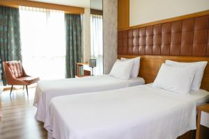 A bed or beds in a room at The Hera Platinum Hotel