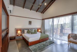 瓦亚纳德Crystal Kuruva Nature Resort & Spa的一间带床和阳台的卧室