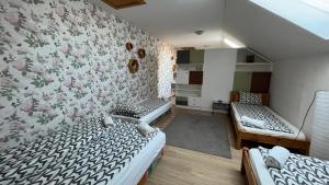 a room with two beds and a wall with flowers at Bozsity Vendégház in Üllés