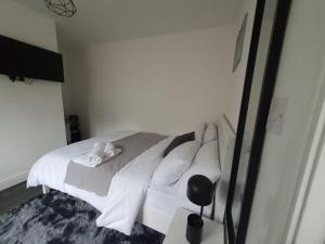 a bedroom with a bed with white sheets and pillows at Private Room & En-Suite Bathroom - Long Term Stays & Contractors Welcomed in Birmingham
