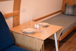 un piccolo tavolo in legno con piatti e bicchieri di The Loft by Wigwam Holidays a Kinloss