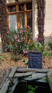 a chalkboard sign in front of a house with flowers at Les Pénates de Loire in Ancenis