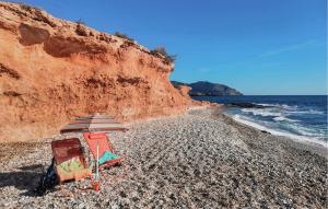 ein Stuhl und ein Sonnenschirm an einem felsigen Strand in der Unterkunft 3 Bedroom Lovely Home In Cartagena in Cartagena + 25 Fotos