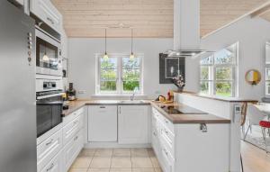 a kitchen with white cabinets and a wooden ceiling at Lovely Home In Dannemare With Sauna in Dannemare +18 photos