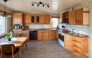 eine Küche mit Holzschränken, einem Tisch und einem Esszimmer in der Unterkunft Beautiful Home In Vestre Gausdal in Vestre Gausdal