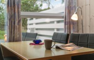 a table with a coffee cup and a book on it at Stunning Apartment In Vejers Strand in Vejers Strand