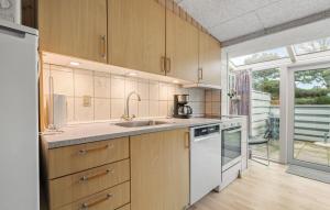 a kitchen with wooden cabinets and white appliances at Stunning Apartment In Vejers Strand in Vejers Strand +10 photos