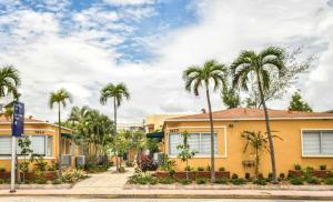 a row of palm trees in front of a yellow building at Family Friendly Condo Steps to Miami Beach with Free Parking in Miami Beach