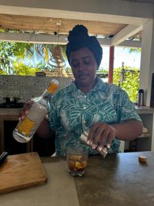 a woman standing at a table with a bottle of alcohol at Cabaña Punta Coral in Rincón