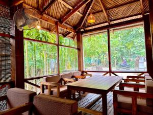 a dining room with a table and chairs and windows at Bruce House in Nonthaburi
