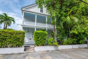 una casa blanca con árboles delante en Creme Brulee Suite, en Key West