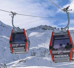 two people riding on a ski lift in the snow at Alpin House Tonale in Passo del Tonale