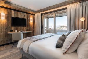 a bedroom with a bed and a desk and a television at Antarès SIRIUS 302 - Ski inski out family apartment in Méribel