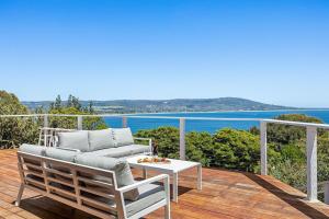 a patio with a couch and a table on a deck at The Peak of Mt Martha Spa and Sunset Views in Mount Martha