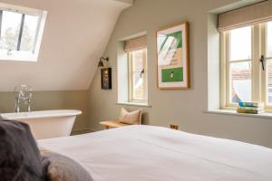 a bedroom with a bed and a bath tub and windows at The Bottle & Glass Inn - Book All 3 Rooms in Henley on Thames
