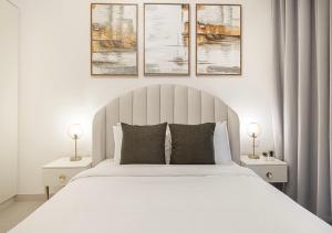 a bedroom with a white bed with three pictures on the wall at Stylish Downtown Retreat, Burj Crown, Opera & Boulevard View in Dubai +50 photos