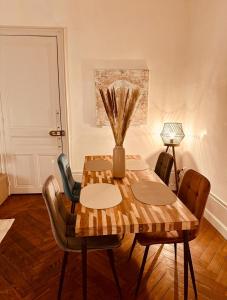 a dining room table with chairs and a vase on it at Le Nid de Forges in Forges-les-Eaux