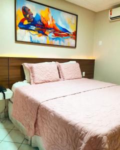 a bedroom with a pink bed with a painting on the wall at Hotel Asa Branca in Belo Jardim