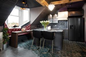 a kitchen with black cabinets and a bar with stools at NYC Loft, Luxury Apartment in Berwick-Upon-Tweed