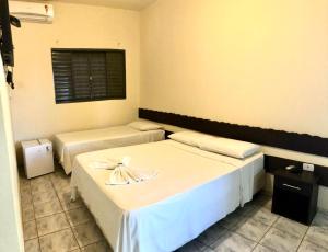 a room with two beds and a window at Bravo Inn Hotel Coxim in Coxim