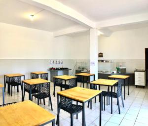 a restaurant with tables and chairs and a kitchen at Bravo Inn Hotel Coxim in Coxim