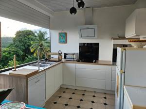 a kitchen with white cabinets and a large window at Villa cosy in Sainte-Luce