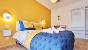 a bedroom with a large blue bed with yellow walls at La grange d'Andre - Spa - 8 personnes - Proche Europa Park in Elsenheim