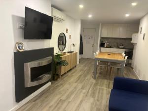 a living room with a table and a tv on a wall at Canyelles BBQ Apartment in Lloret de Mar