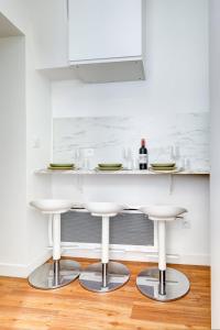 une cuisine avec un comptoir blanc et deux tabourets de bar dans l'établissement 402 Suite Netter - Superbe Studio à Paris, à Paris