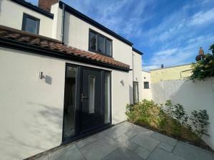 a white house with a black door on a patio at Cromer Coastal Cottage in Cromer
