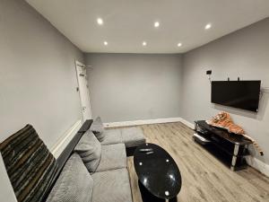 a living room with a couch and a flat screen tv at Monyhull Homestay - near City centre Kingsheath NIA NEC BHX in Birmingham