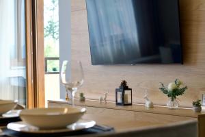 a table with wine glasses and a television on a wall at Forest Zlatni Bor in Zlatibor