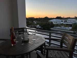 a wooden table with wine glasses on a balcony at Luxury 2 Bed 2 Bath Waterfront Condo with Patio Sunsets Gym and Parking in Sarasota