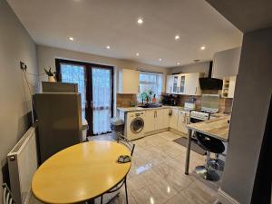 a kitchen with a table and a wooden table in it at Monyhull Homestay - near City centre Kingsheath NIA NEC BHX in Birmingham