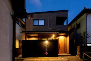 a house with a gate in front of it at night at 貸し切り宿 世紡 YOTSUMUGI sakazuki and iyasaka in Yufuin