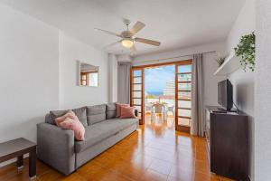 a living room with a couch and a ceiling fan at Costa Adeje Garden City Sea View in Csta Adje