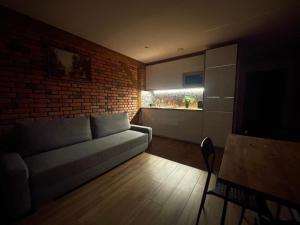 a living room with a couch and a brick wall at Apartamenty MOGADOR in Szczytna +17 photos
