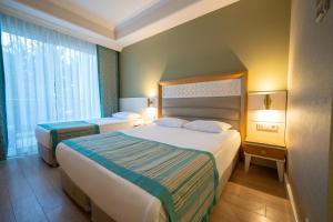 a hotel room with two beds and a window at Karmir Resort & Spa - Ultra All Inclusive in Kemer
