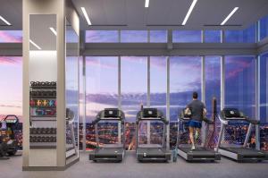 un hombre parado en un gimnasio mirando por la ventana a una ciudad en Stunning Apt with City Views, en Boston