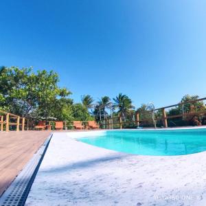 una piscina con acqua azzurra e palme di Vila das Mangabeiras Corumbau a Corumbau