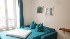Una habitación con un sofá azul con almohadas. en Studio lumineux au charme parisien, en Vincennes