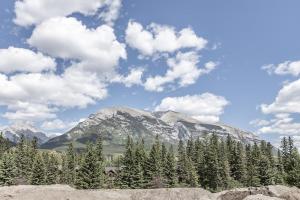 a mountain in the distance with trees and clouds at New 1Bd Luxe King Suite with Superb Mtn View in Canmore