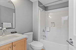 a white bathroom with a toilet and a sink at Freshly Remodeled - 2 King Beds- Breathtaking Views in Canmore