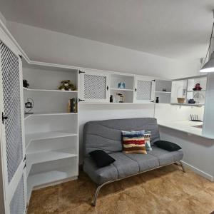 a living room with a gray couch and white shelves at Casa Criso Puerto del Rosario in Puerto del Rosario
