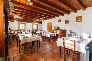 a restaurant with white tables and chairs and wooden ceilings at La Pietra Nera in San Giovanni Ilarione