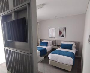 a hotel room with two beds and a flat screen tv at Guemes Hotel & Spa in Salta