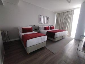 a hotel room with two beds with red pillows at Guemes Hotel & Spa in Salta