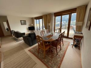 a living room with a table and a couch at Large 3 bed apartment with mountain views, pool and gym in Chateau-d'Oex