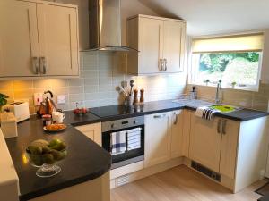 a kitchen with white cabinets and a black counter top at The View Cottage - Tennis Court - Nr Frome, Longleat in Frome